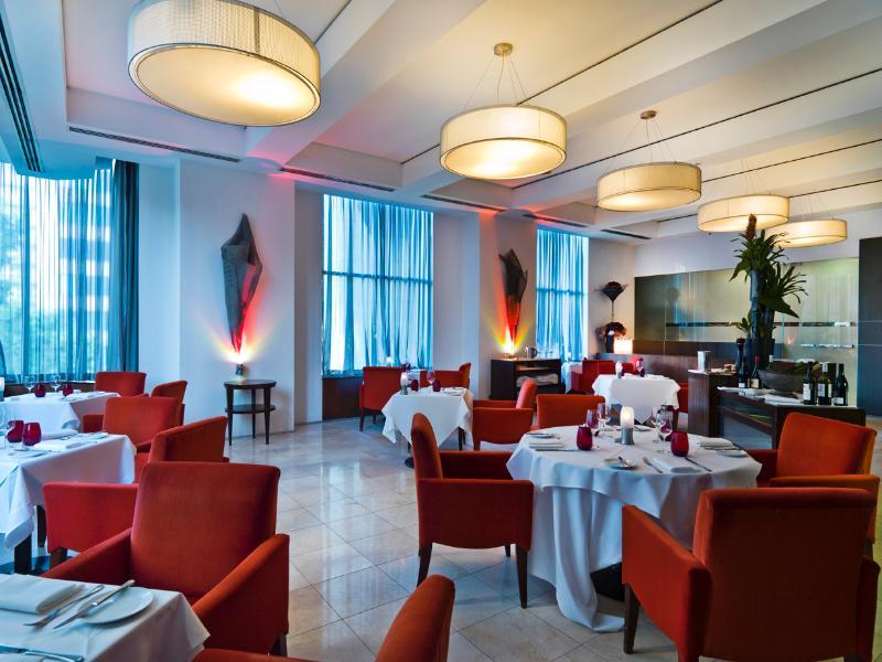 Amora Hotel Jamison Sydney Luaran gambar The photo shows an elegant restaurant interior. The space features stylish red chairs arranged around white tablecloth-covered tables. There are decorative elements like sculptures or artworks on the walls, and large windows covered with sheer curtai